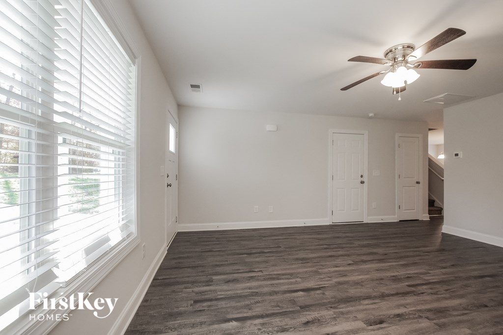 an empty living room with a ceiling fan and a large window
