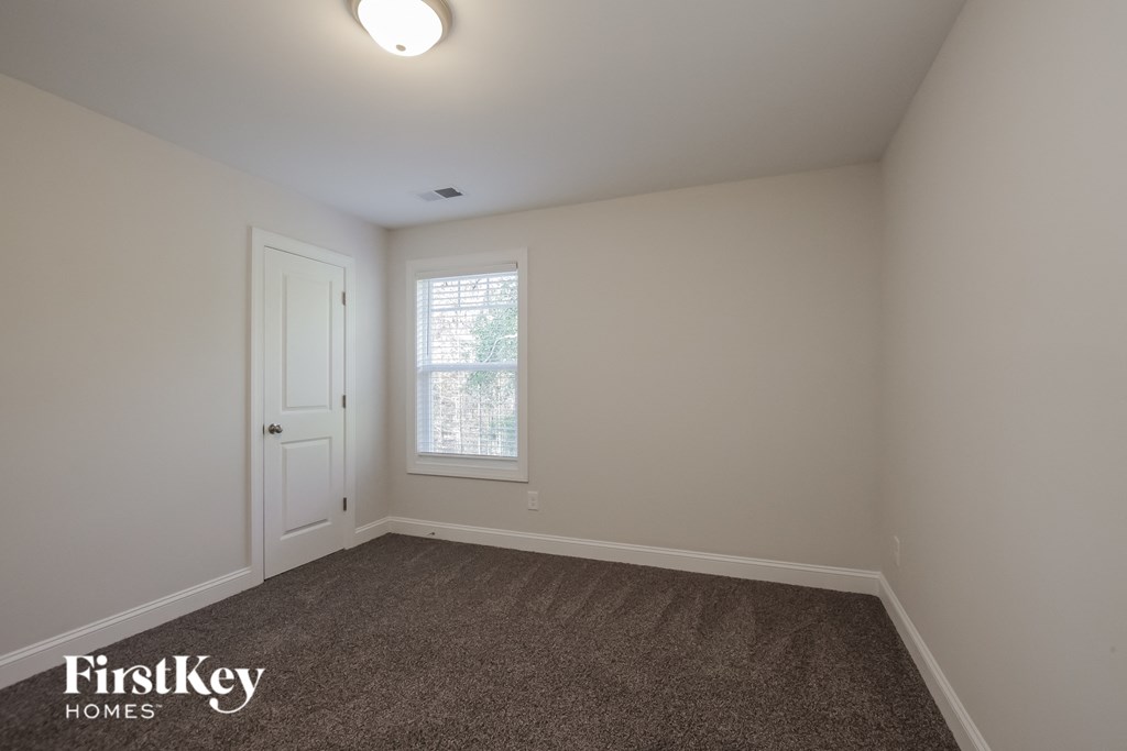 a bedroom with white walls and carpet and a window