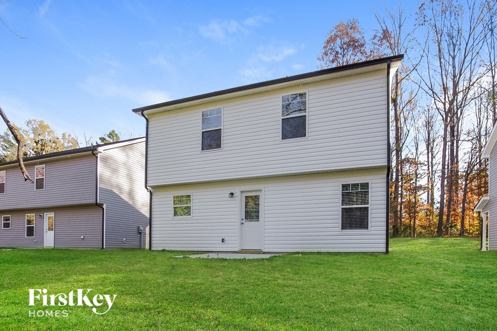 side view of a white house with gray siding and a green lawn
