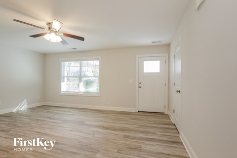 an empty living room with a ceiling fan and a door