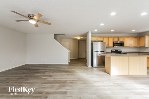 A spacious kitchen and living room with a wood floor and a ceiling fan.