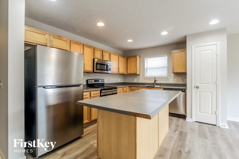 A kitchen with wooden cabinets and a stainless steel refrigerator.
