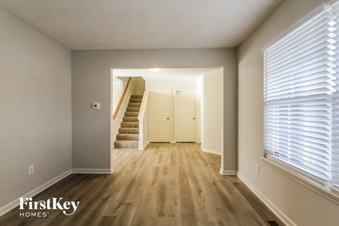 A hallway with wooden floors and a staircase leading to another room.