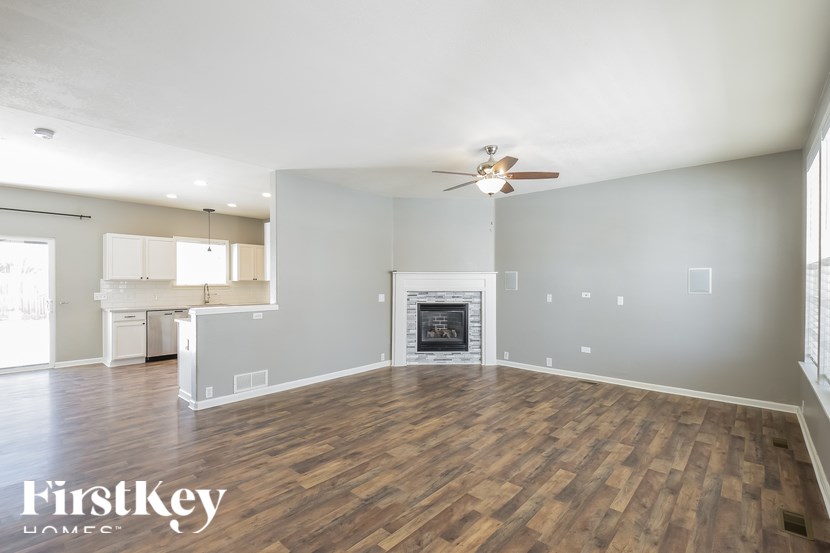 A spacious living room with a fireplace and a ceiling fan.