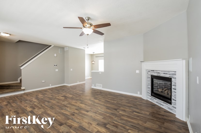 A spacious room with a fireplace and a ceiling fan.