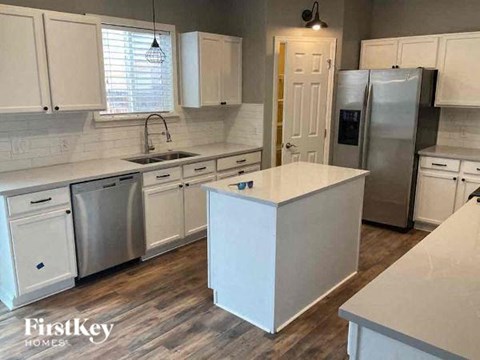 A kitchen with white cabinets and a white island.