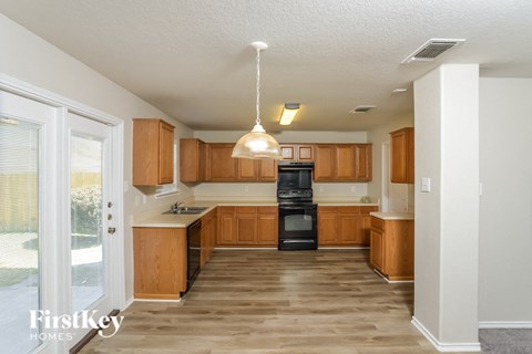 a kitchen with wooden cabinets and black appliances and a sliding glass door