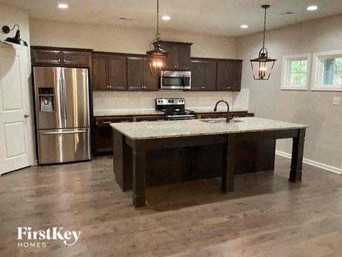 A kitchen with a refrigerator, stove, and cabinets.