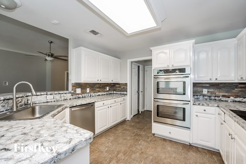 a white kitchen with marble counter tops and stainless steel appliances