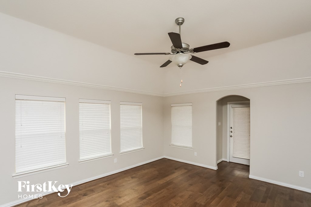 an empty living room with a ceiling fan and windows
