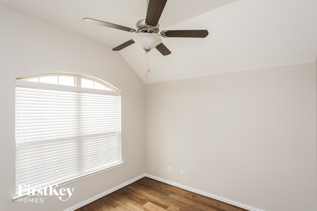 a bedroom with a ceiling fan and a large window