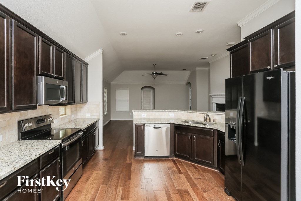a kitchen with wood flooring and stainless steel appliances