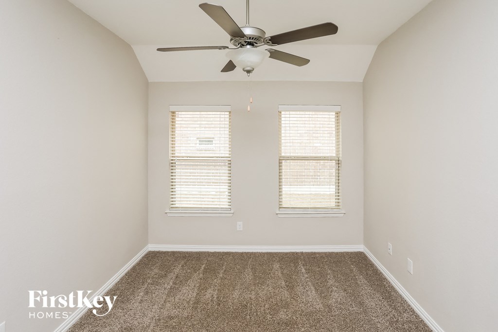 a empty room with a ceiling fan and two windows