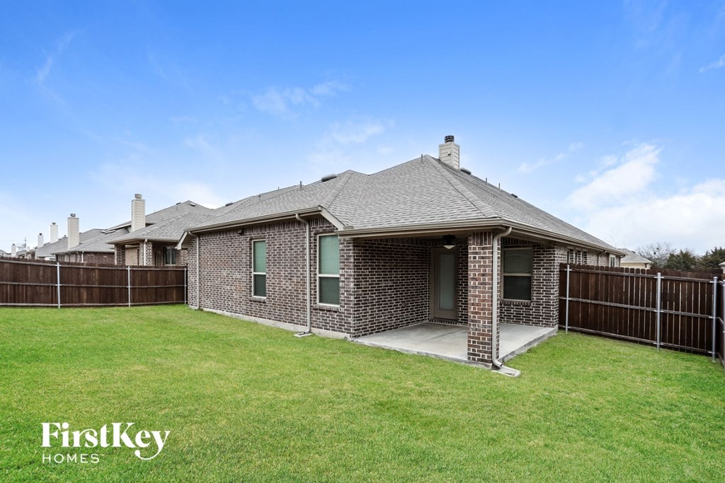 a backyard with a brick house and a green lawn