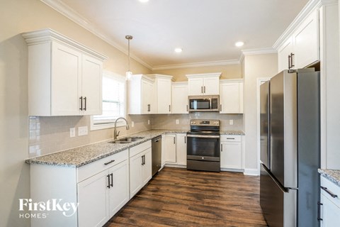 A kitchen with white cabinets and a granite countertop.