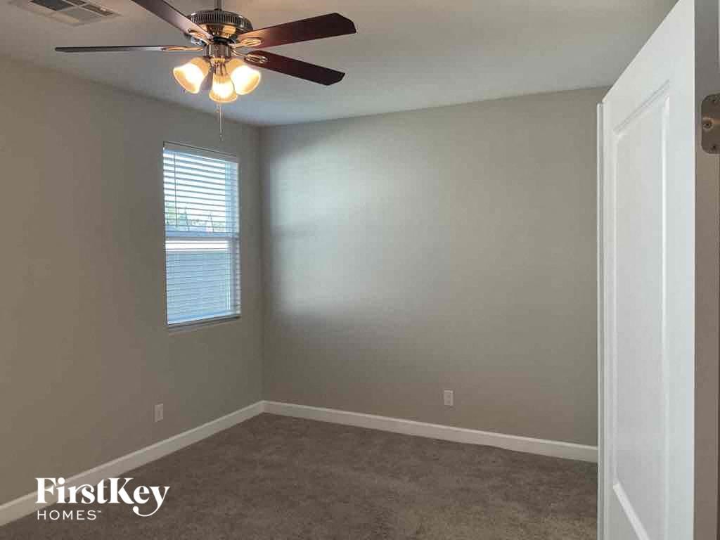 A room with a ceiling fan and a window with blinds.
