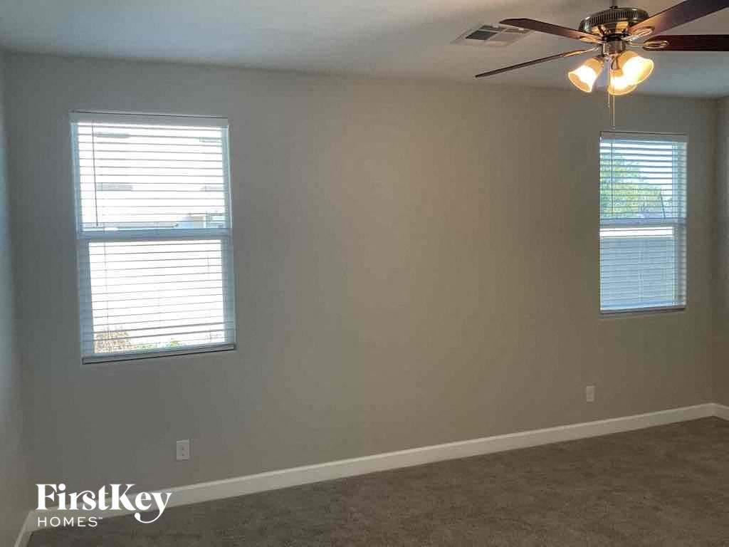 A room with a ceiling fan and two windows.
