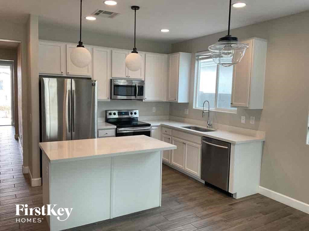 A kitchen with a refrigerator, microwave, oven, and sink.