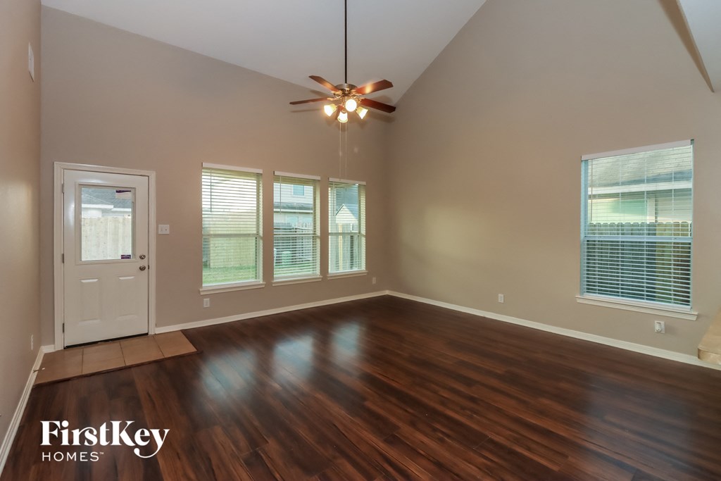 an empty living room with wood floors and a ceiling fan