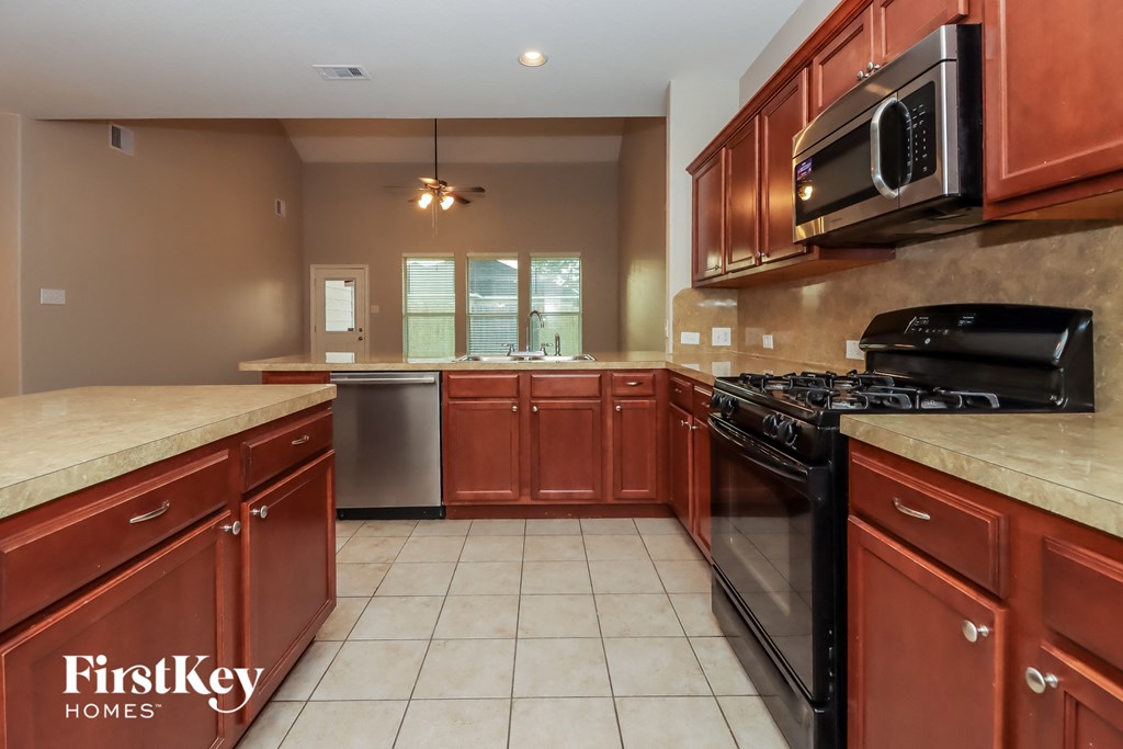 a kitchen with wood cabinets and black appliances and tile floors