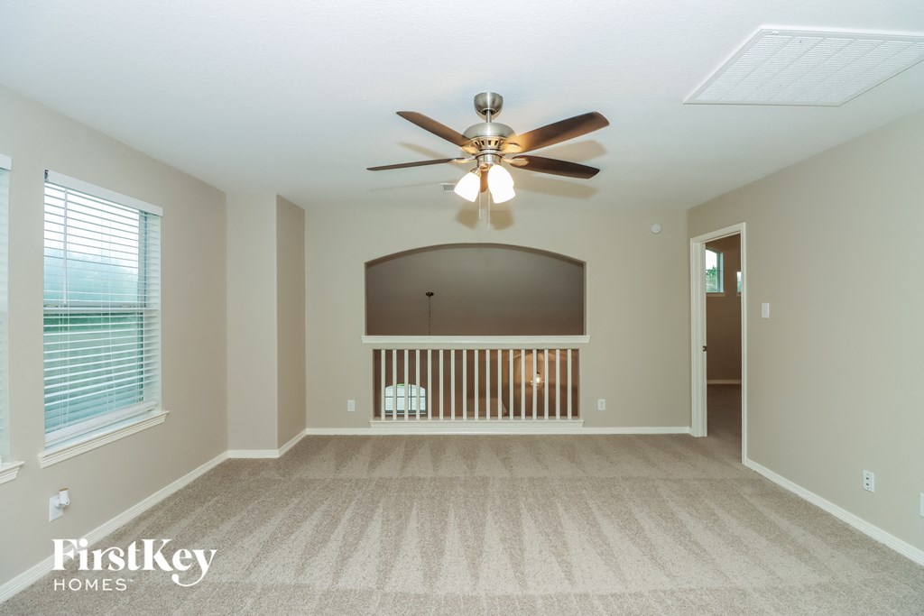 an empty living room with a ceiling fan and a window