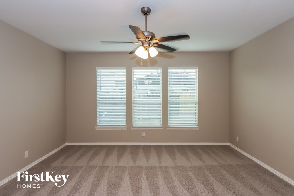 an empty room with a ceiling fan and three windows