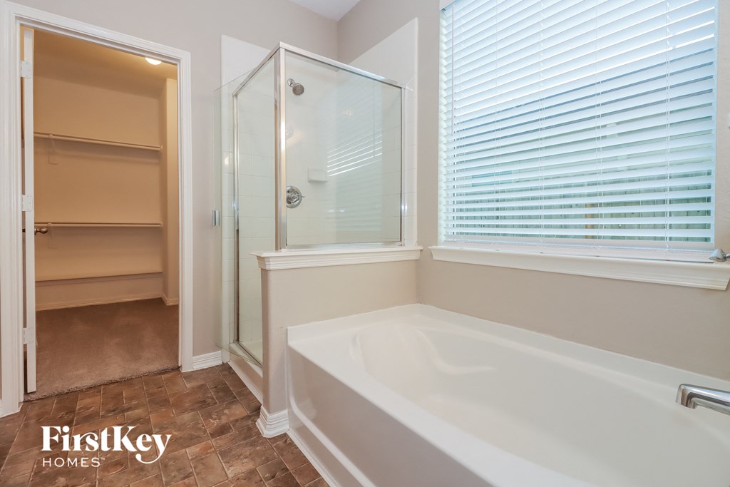 a bathroom with a tub and a shower and a closet