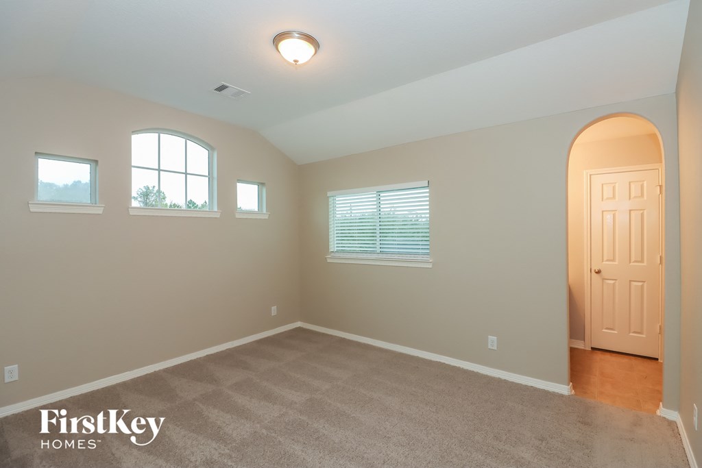 a room with a carpeted floor and a door and three windows