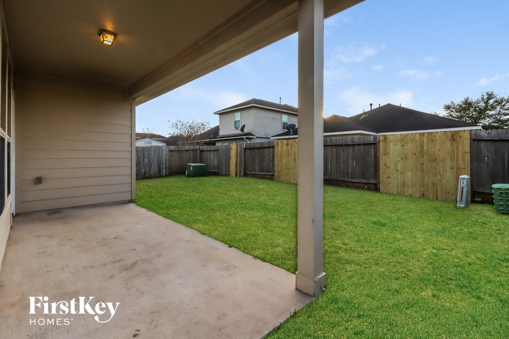 the backyard of a house with a fence and a concrete driveway