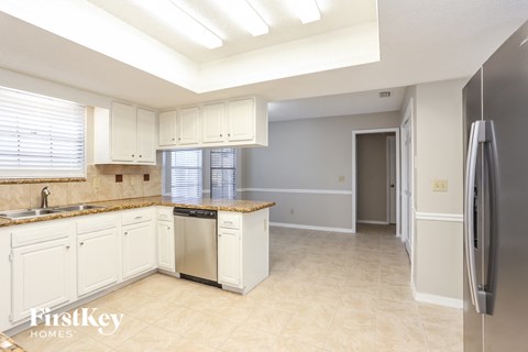 A kitchen with white cabinets and a refrigerator.
