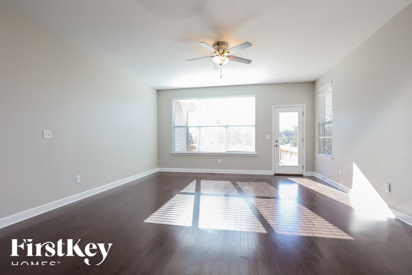 A spacious room with a ceiling fan and a large window.