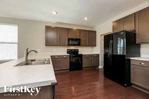 A kitchen with a black refrigerator and brown cabinets.