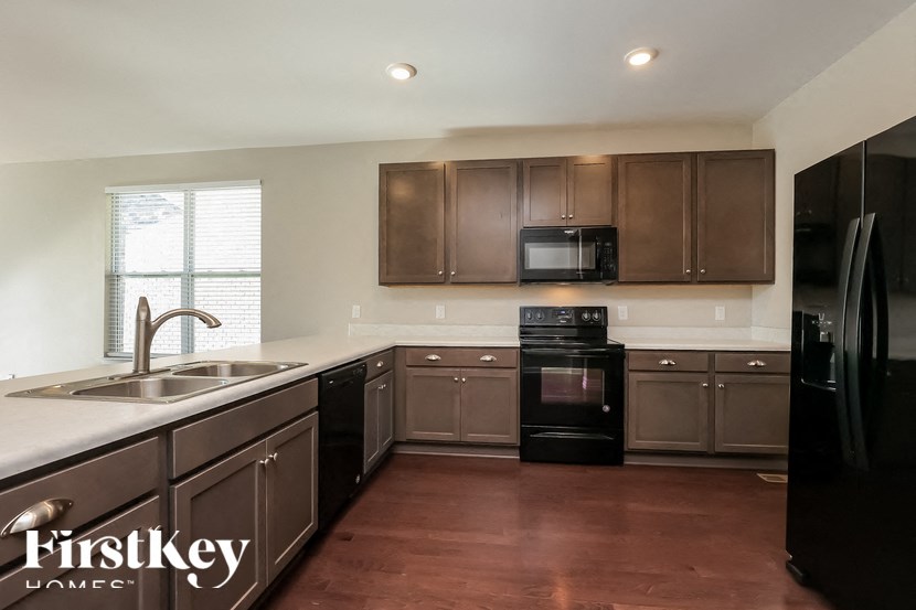 A kitchen with brown cabinets and a black refrigerator.