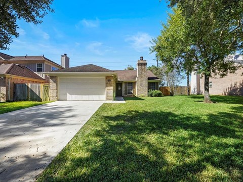 a house with a driveway and a yard with a tree