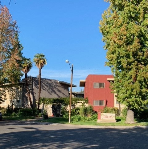 A red building with the word "PALMS" on a stone slab in front of it.