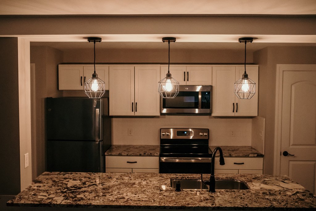a kitchen with white cabinets and black appliances and lights