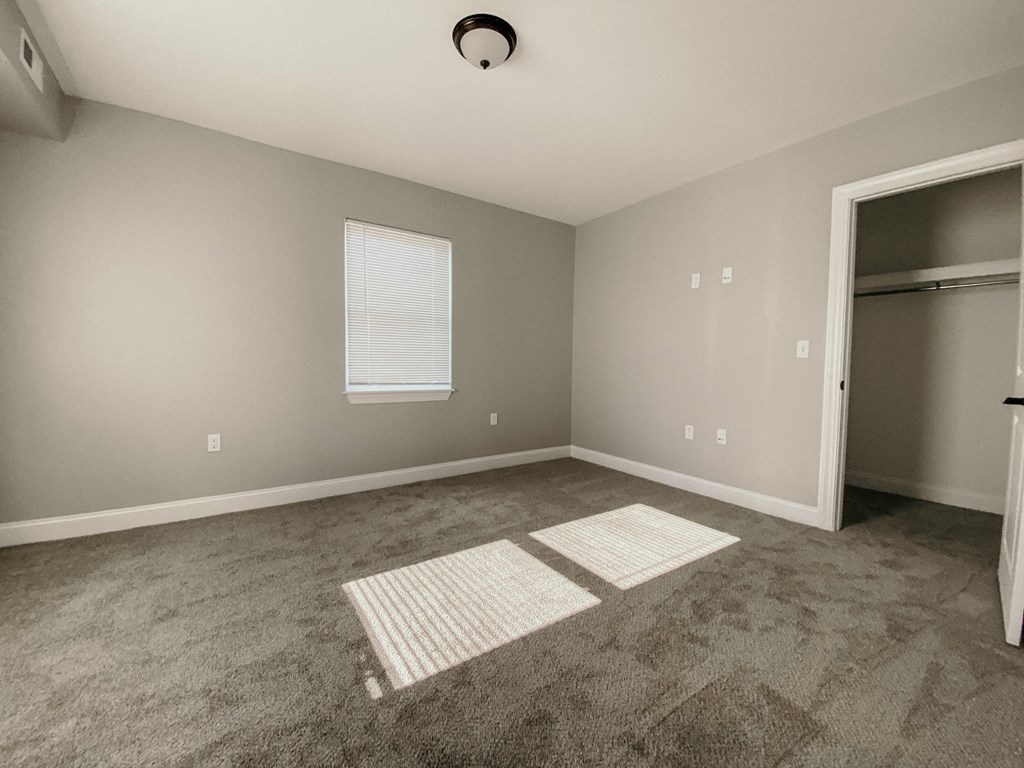 an empty room with carpet and a door to a closet