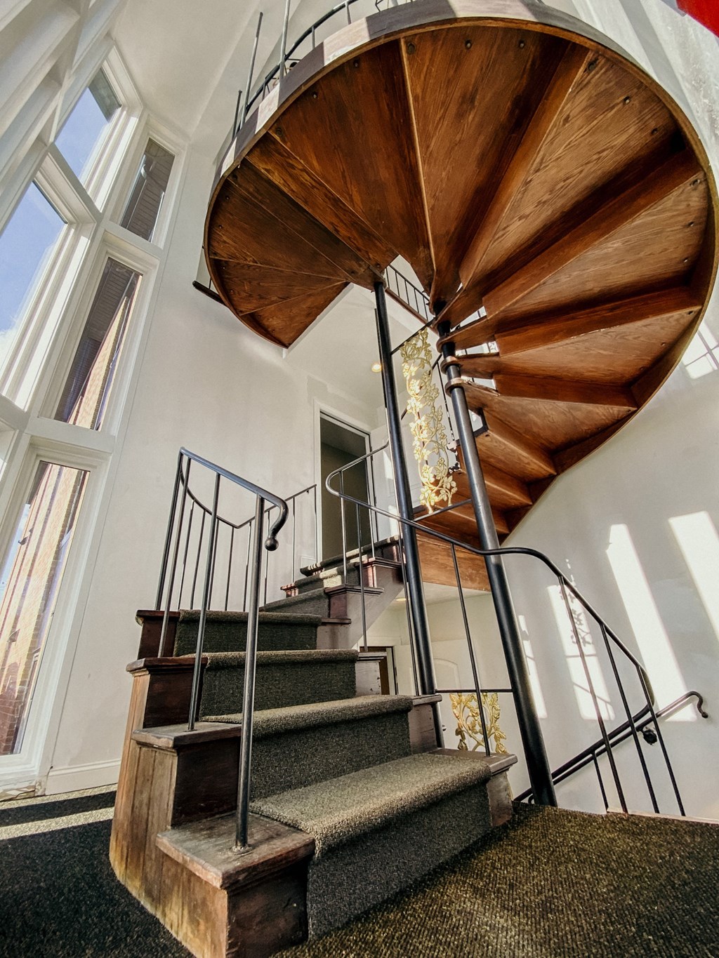 a spiral staircase with wood and metal railings and a wooden windmill spiral staircase
