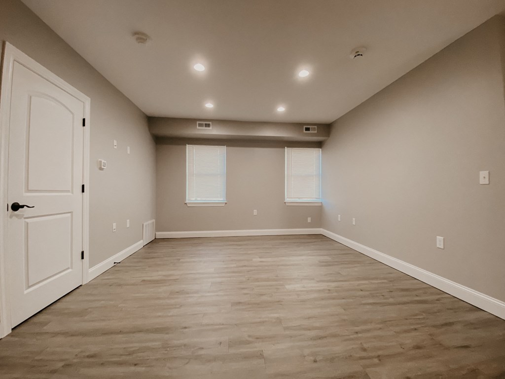 an empty living room with a white door and a window