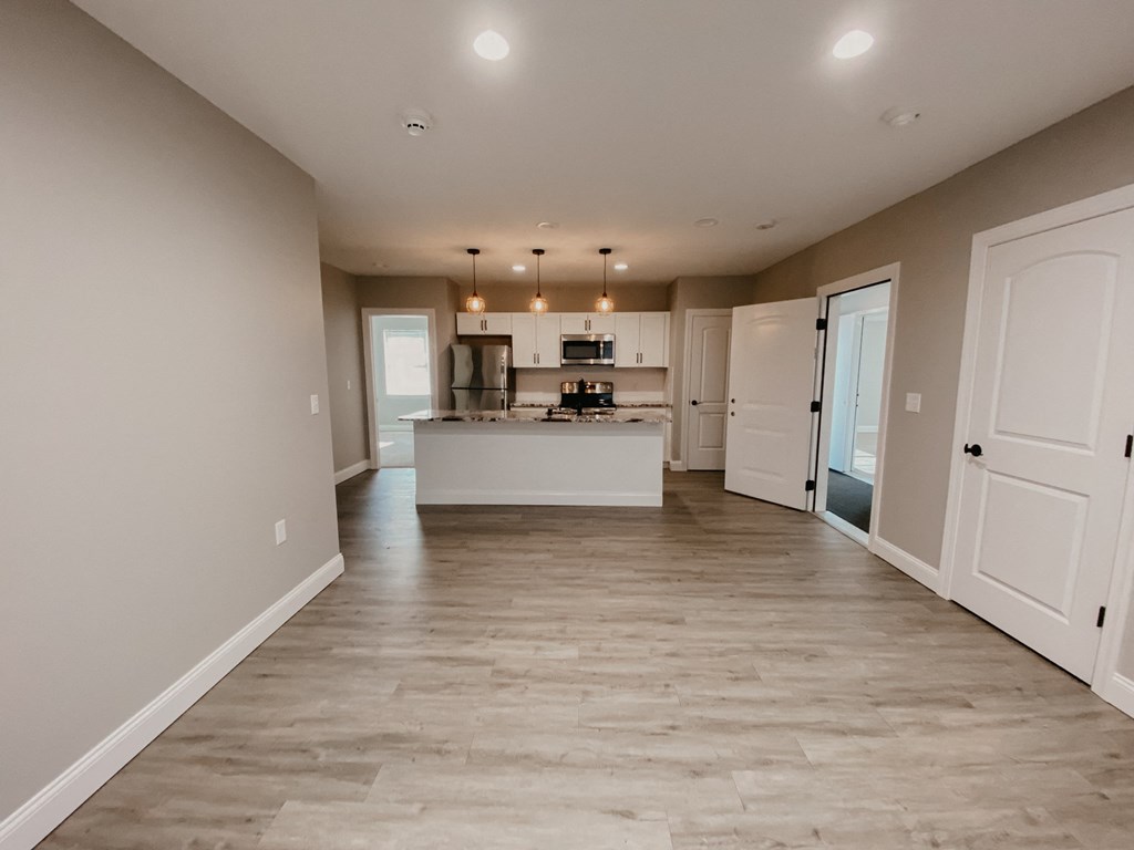 an empty living room and kitchen with white doors and a kitchen island