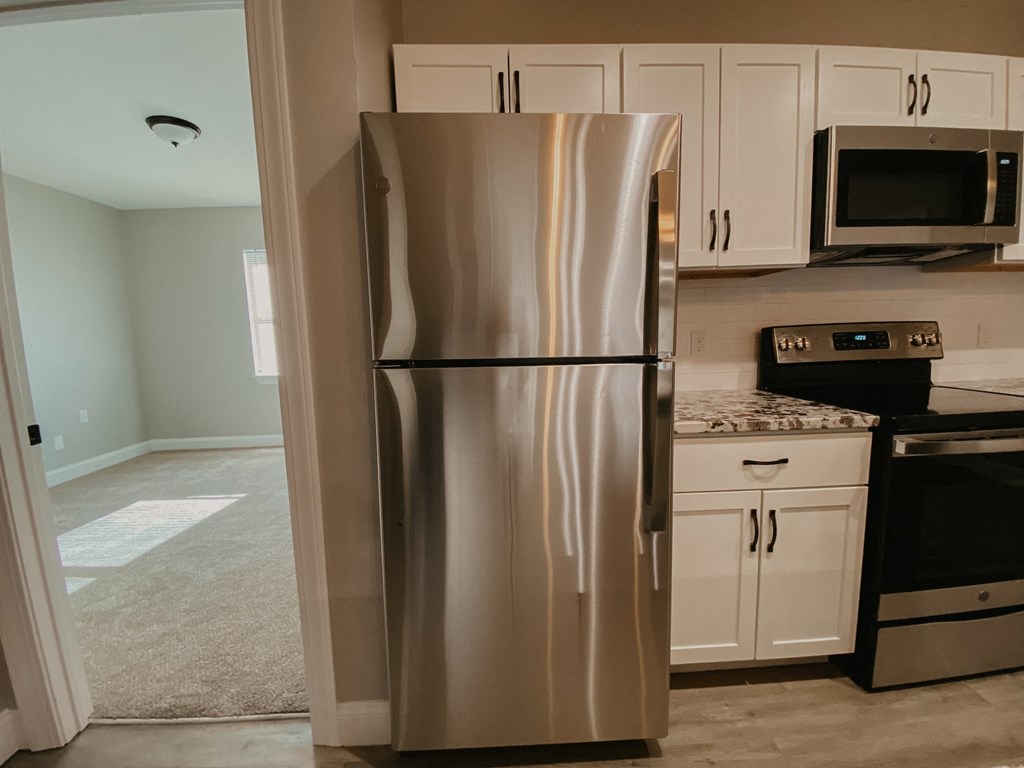 a stainless steel refrigerator in a kitchen with white cabinets
