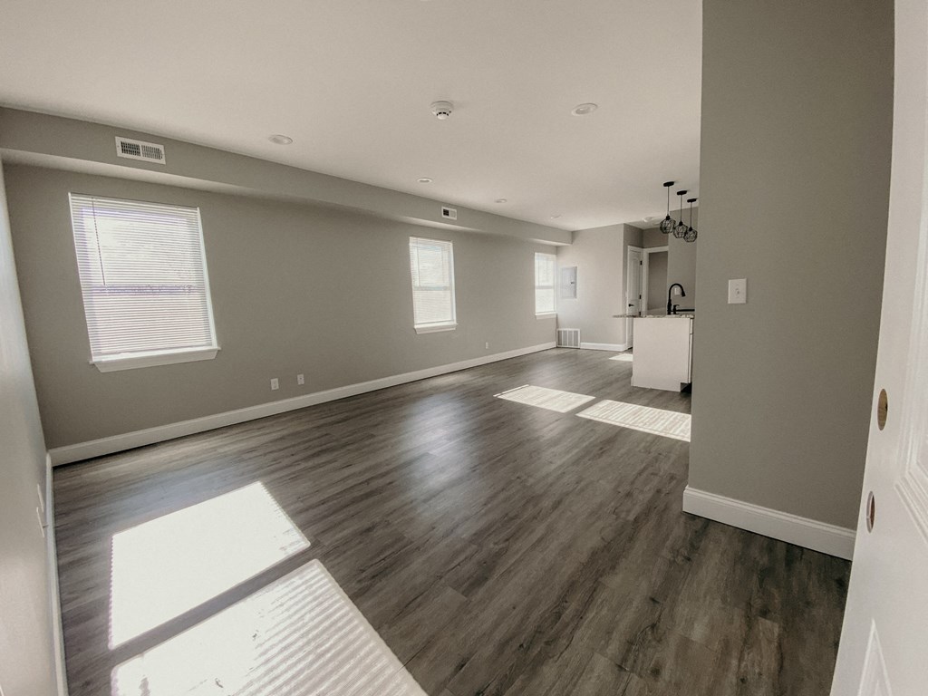 the living room and kitchen of a new home with wood floors and grey walls