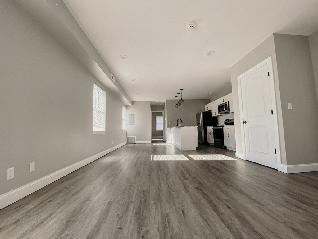 an empty living room and kitchen with vinyl flooring