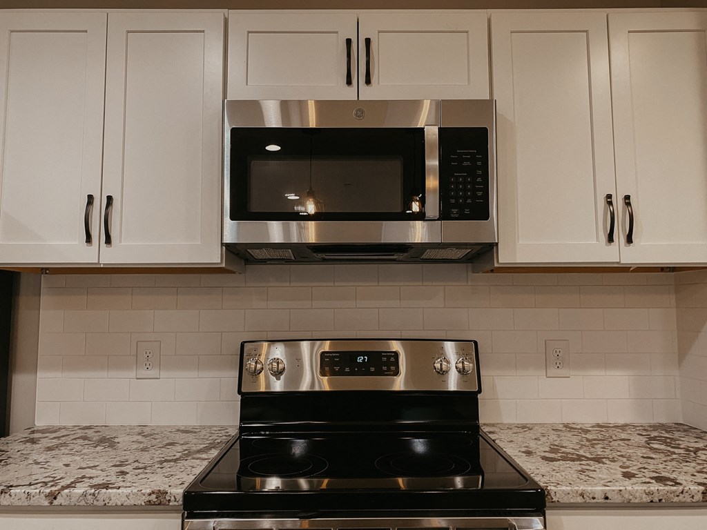 a kitchen with white cabinets and a black stove