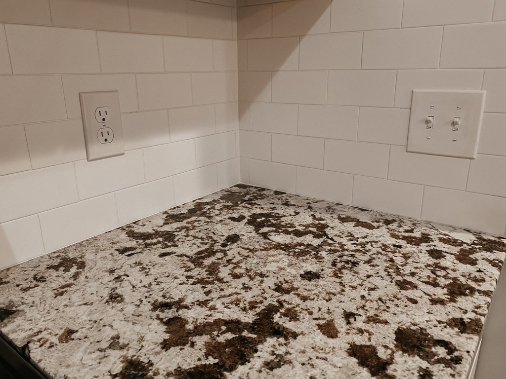 a kitchen with a granite counter top and white tile walls
