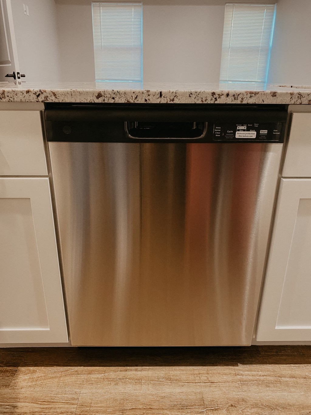 a stainless steel dishwasher in a kitchen with white cabinets