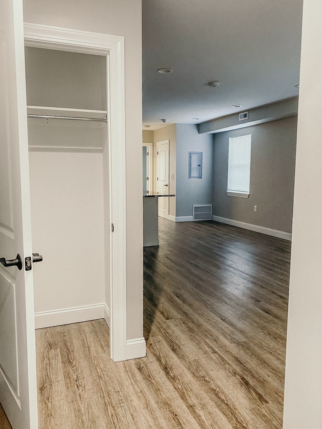 an empty living room and kitchen with wood flooring