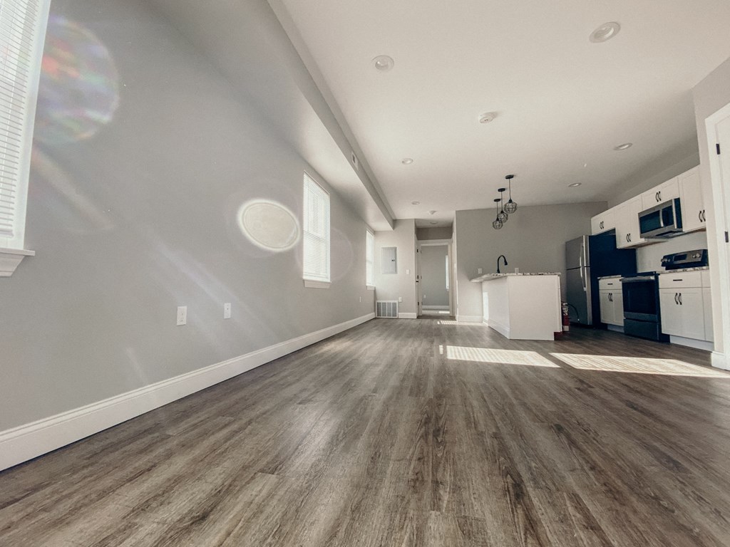 the living room and kitchen of a new home with white walls and wood flooring