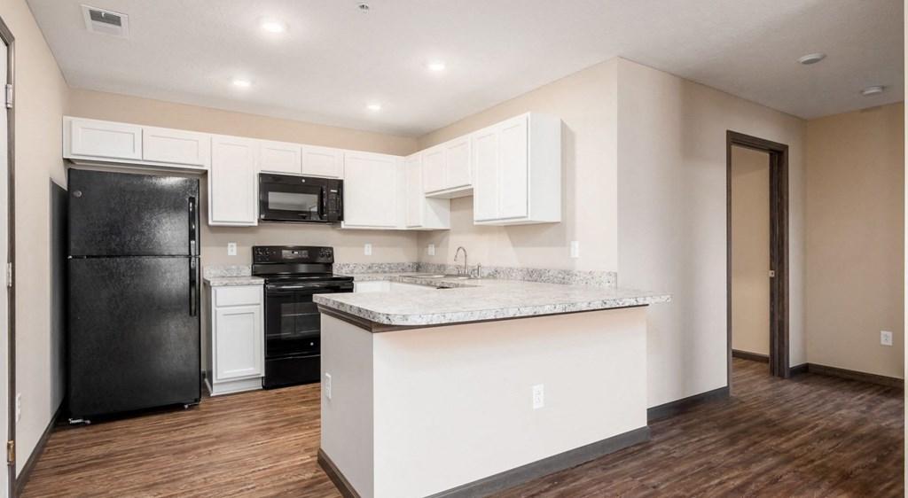 a kitchen with white cabinets and a black refrigerator