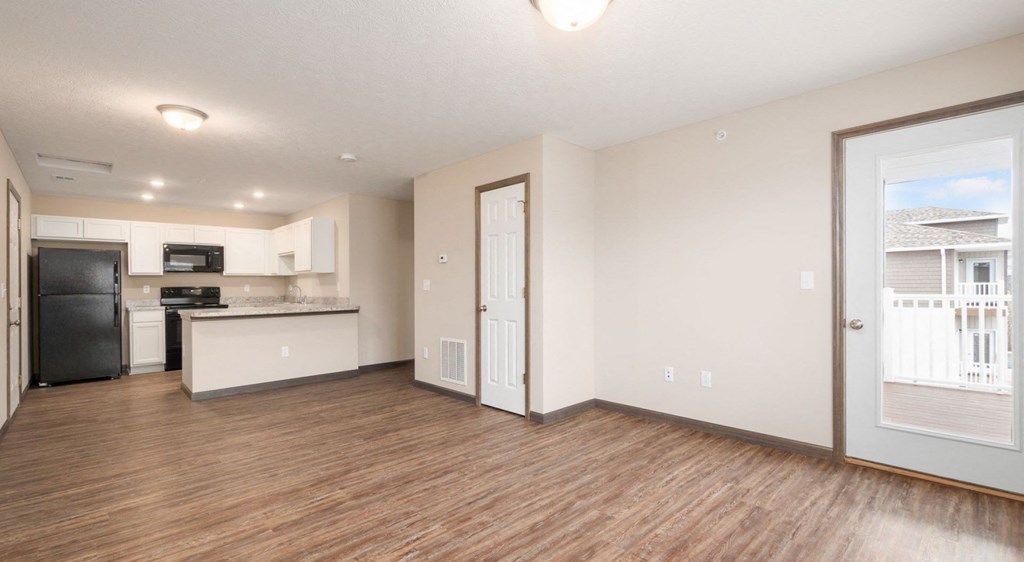 a living room with a kitchen and a door to a balcony